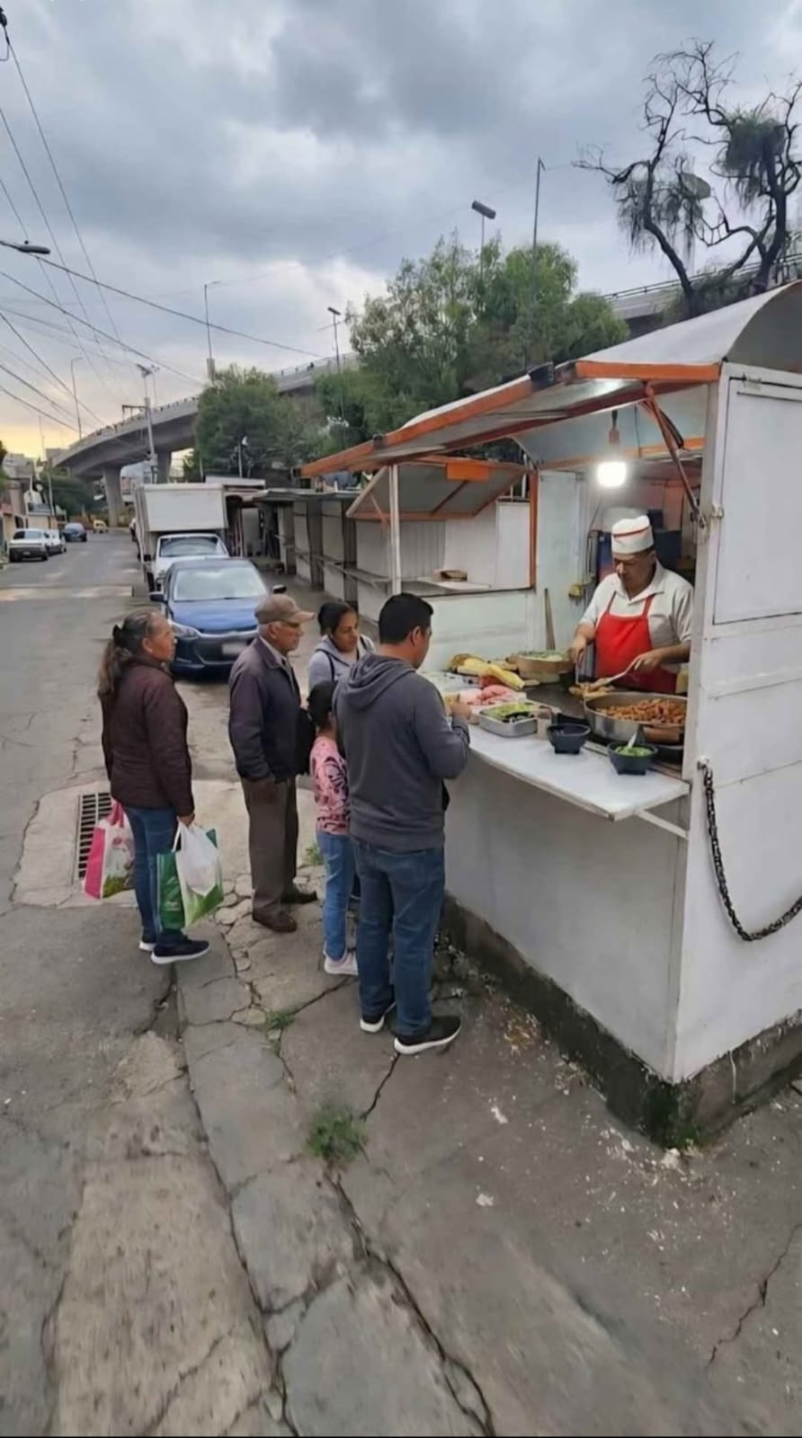 puesto de comida en la calle vendiendo tacos con clientes alrededor ideal para un traspaso negocio funcionando